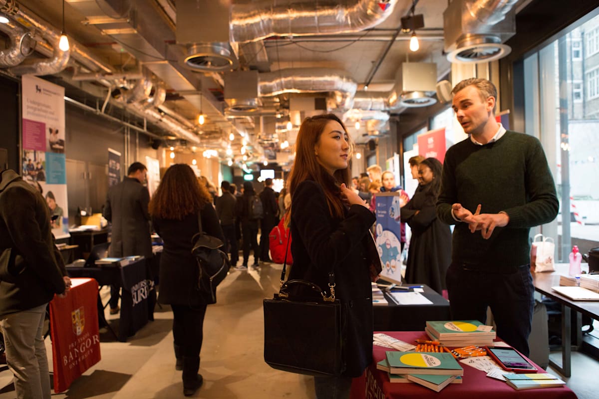 Image of international student speaking to a man at one of the university stands