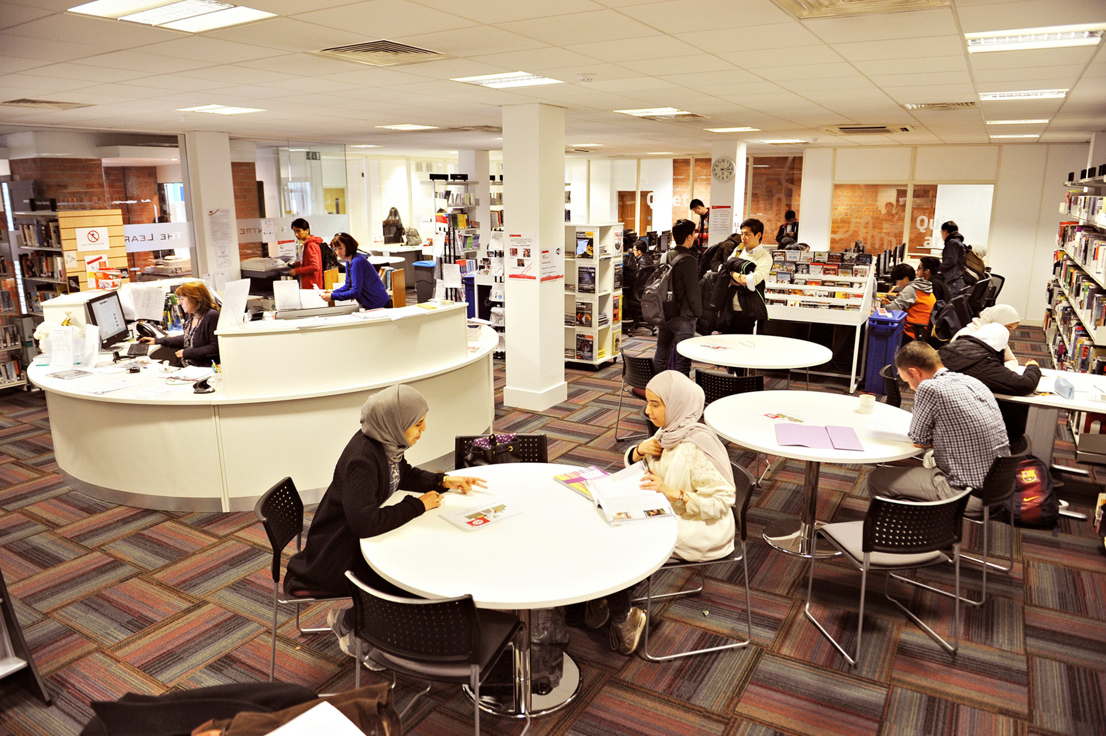 International students working in Learning Resource Centre with help desk