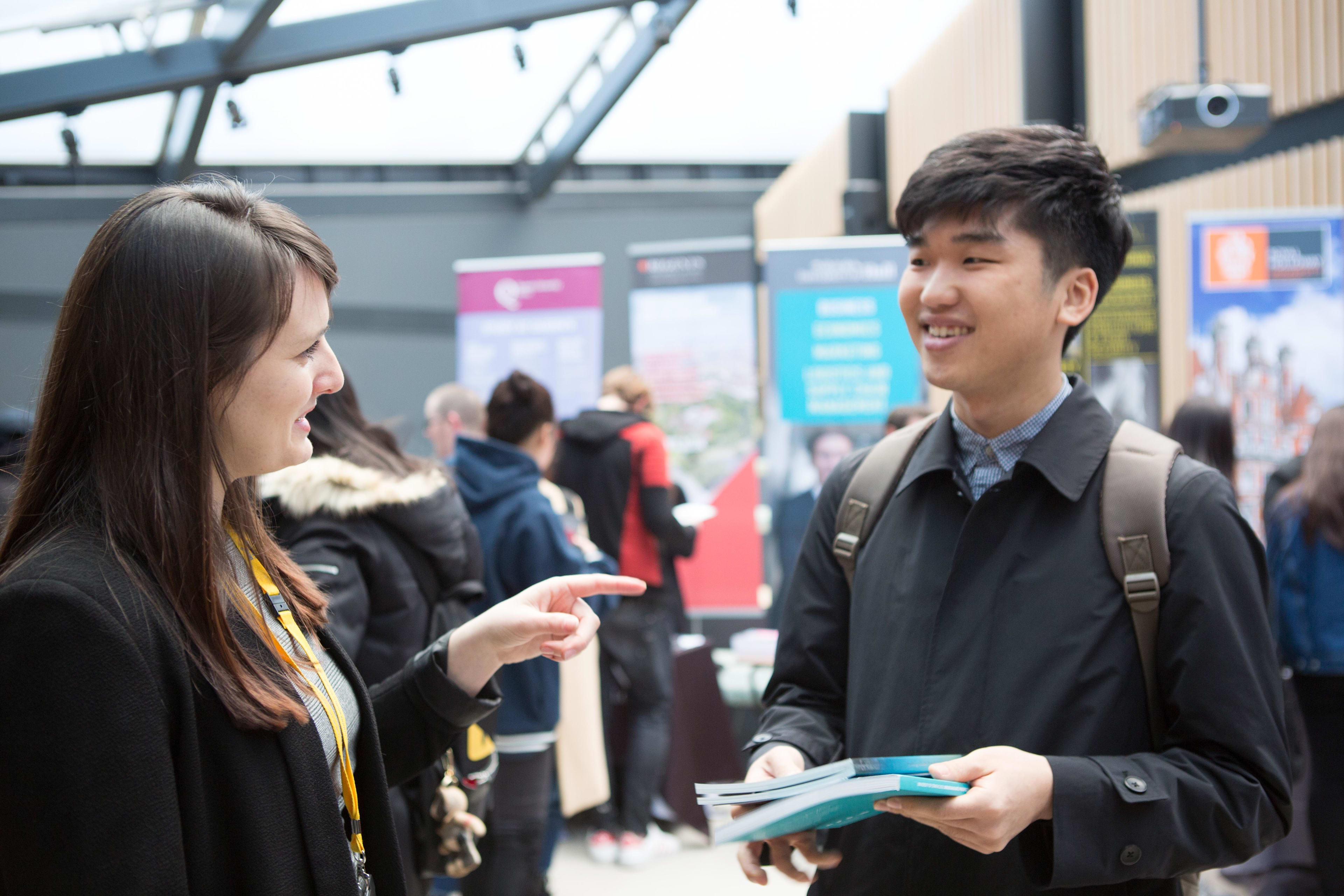 International student speaking to representative at University exhibition stand