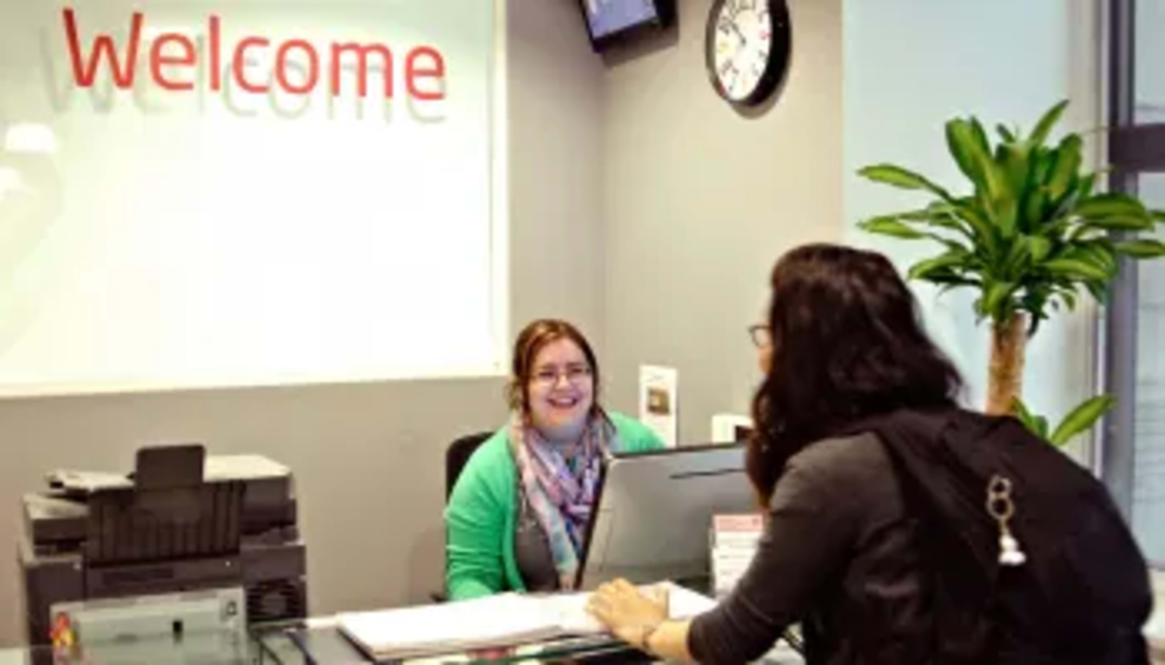 Student at welcome desk speaking with staff member
