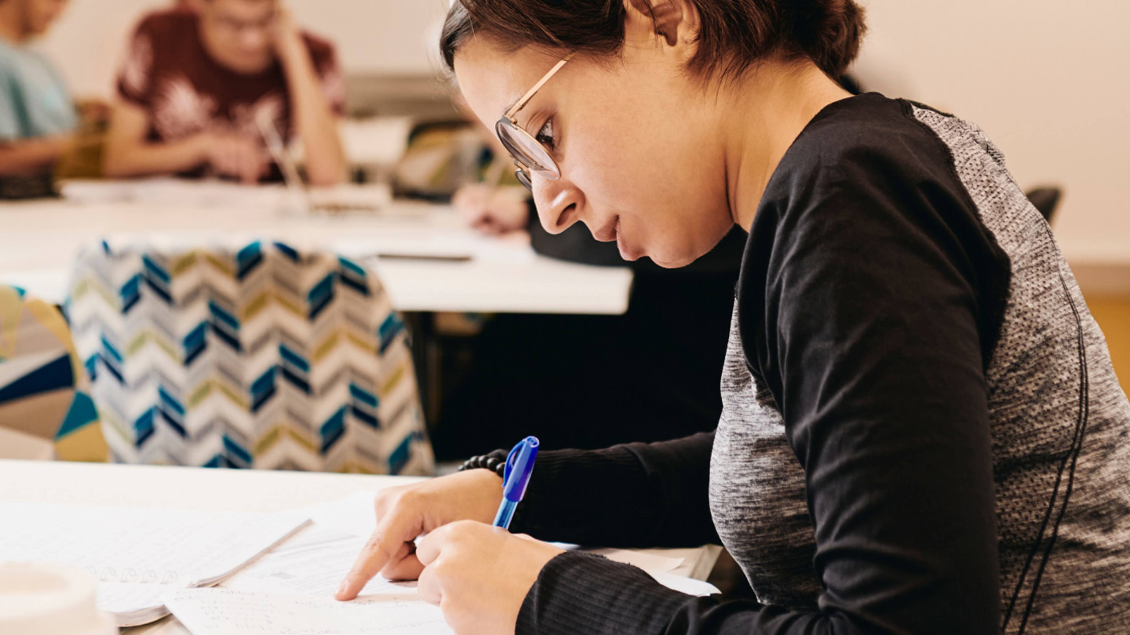Student writing at desk