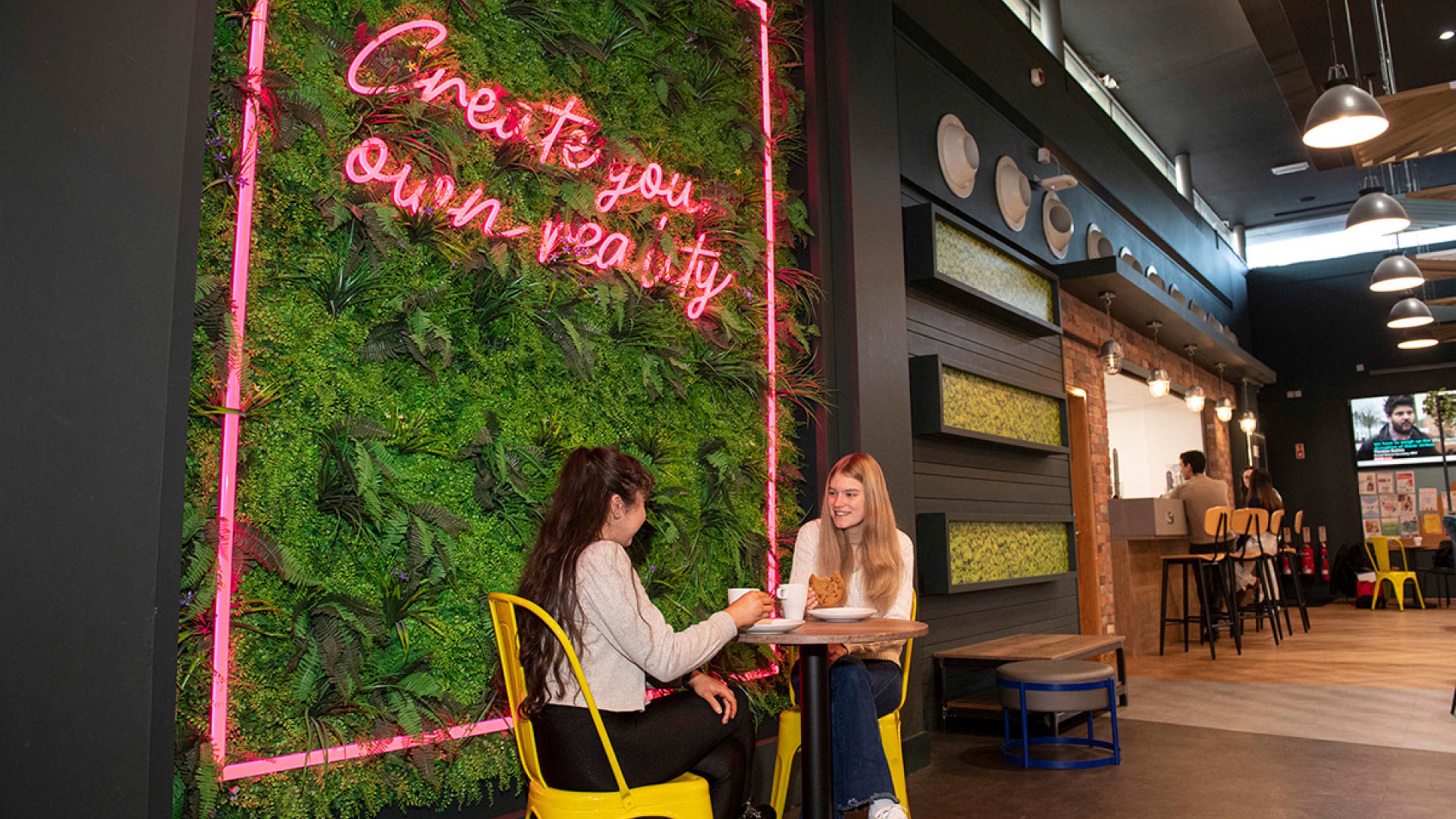 Two friends talking and having coffee together in the cafe at Queen's University Belfast accommodation