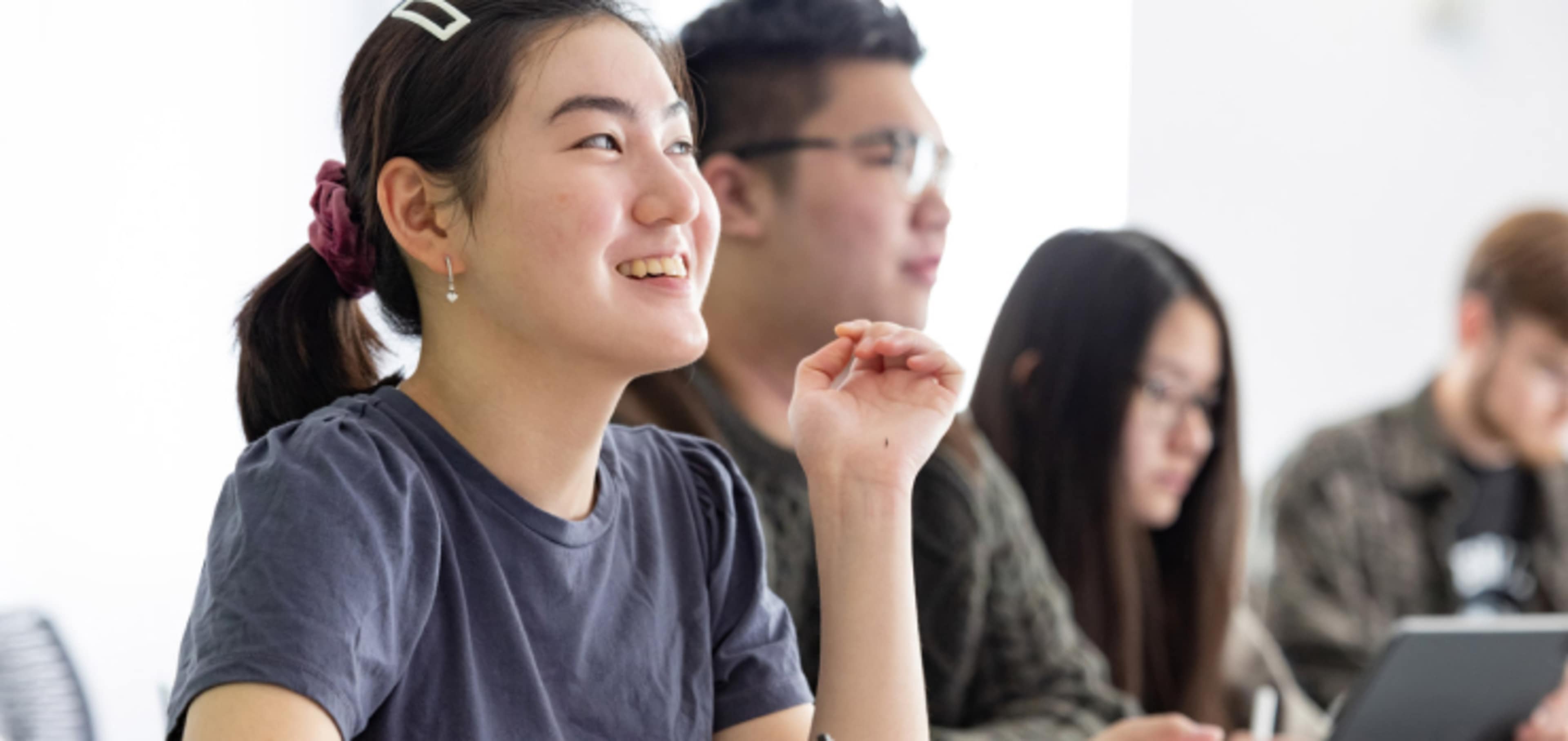 English language sat in study space smiling and talking with other students