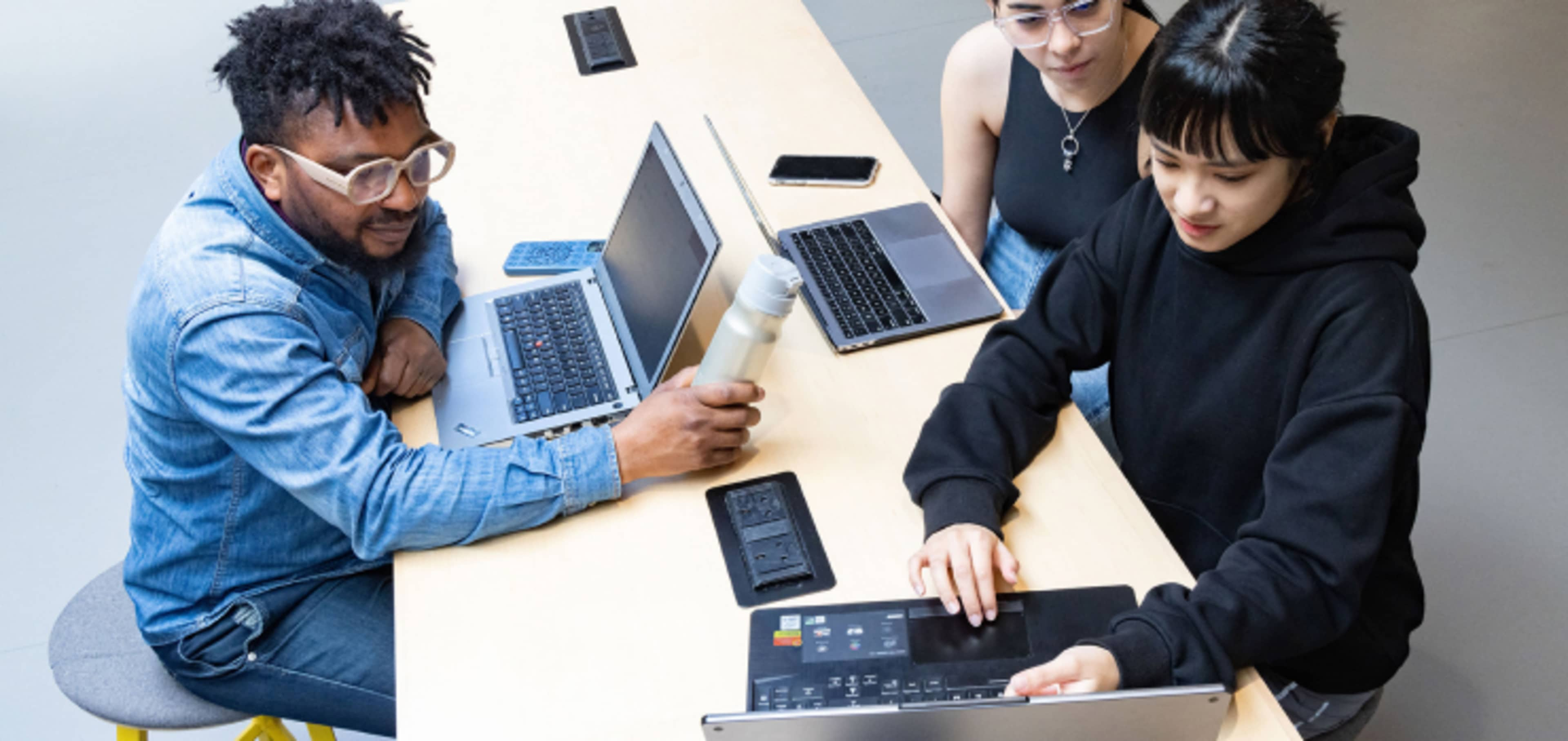 Undergraduate students working together at desk comparing notes on computers