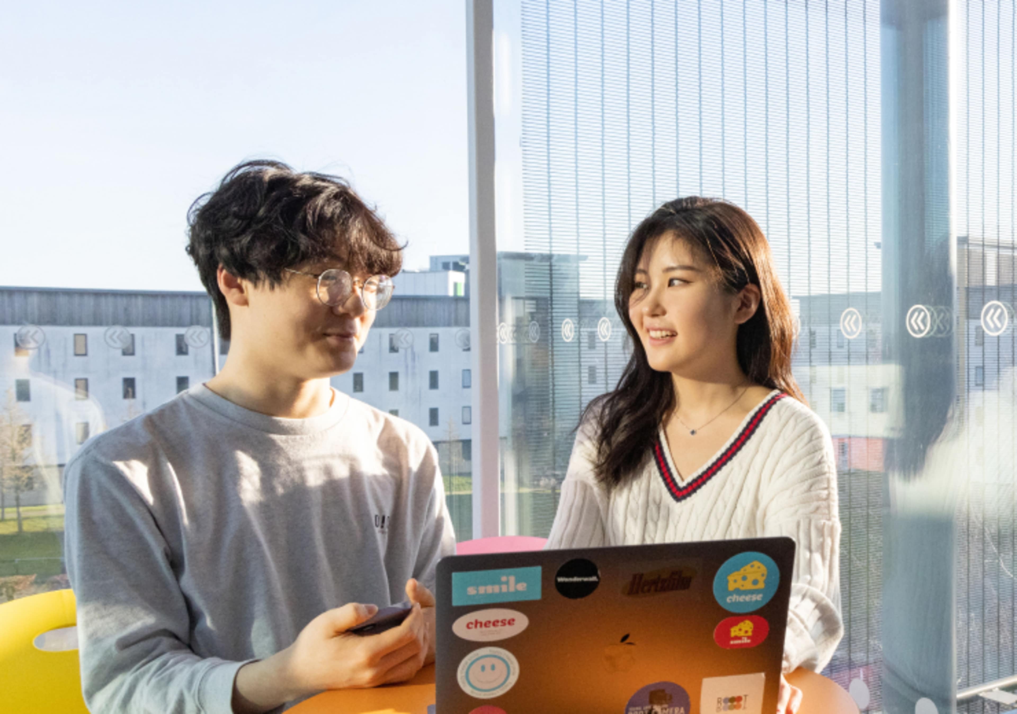 Two young asians discussing in front of a laptop