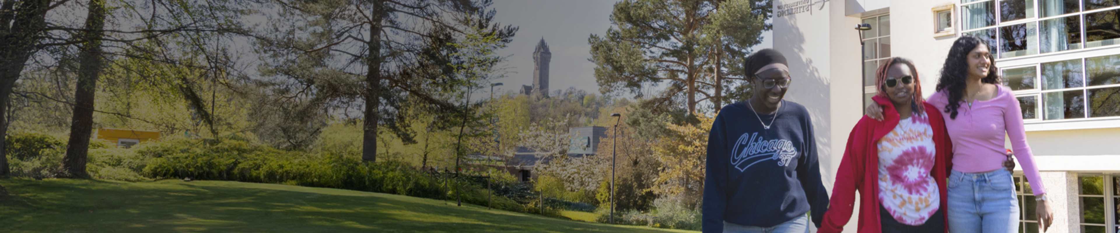 Three international students walking around campus  ground with Stirling Castle as backdrop