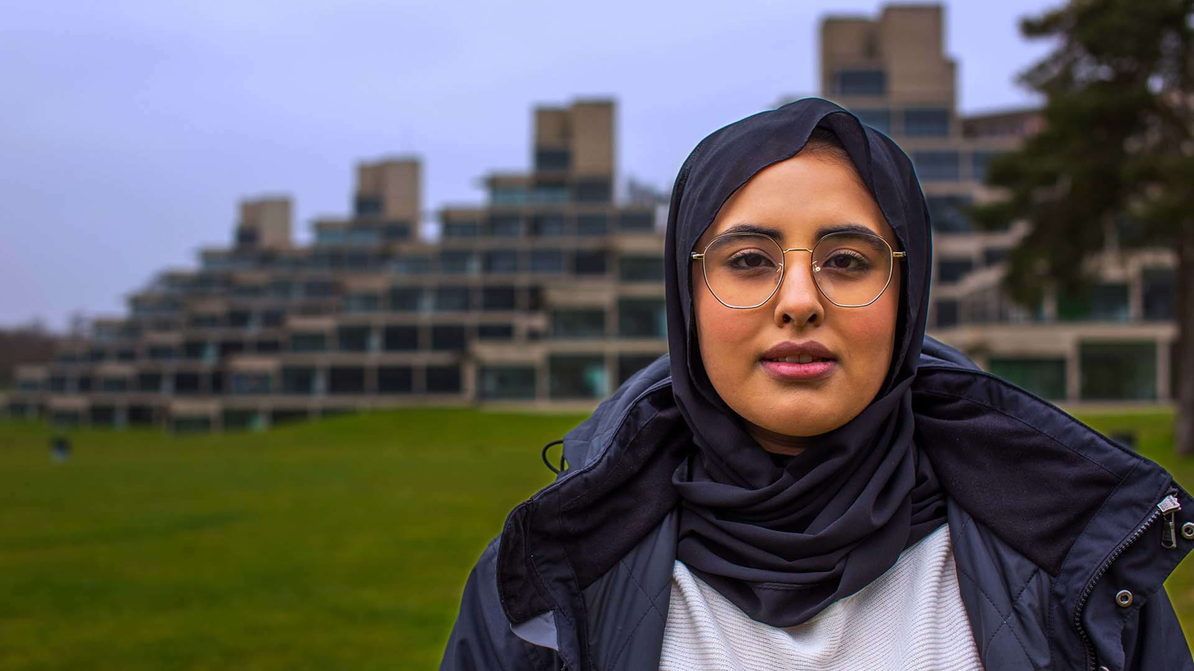 Student standing against UEA campus 