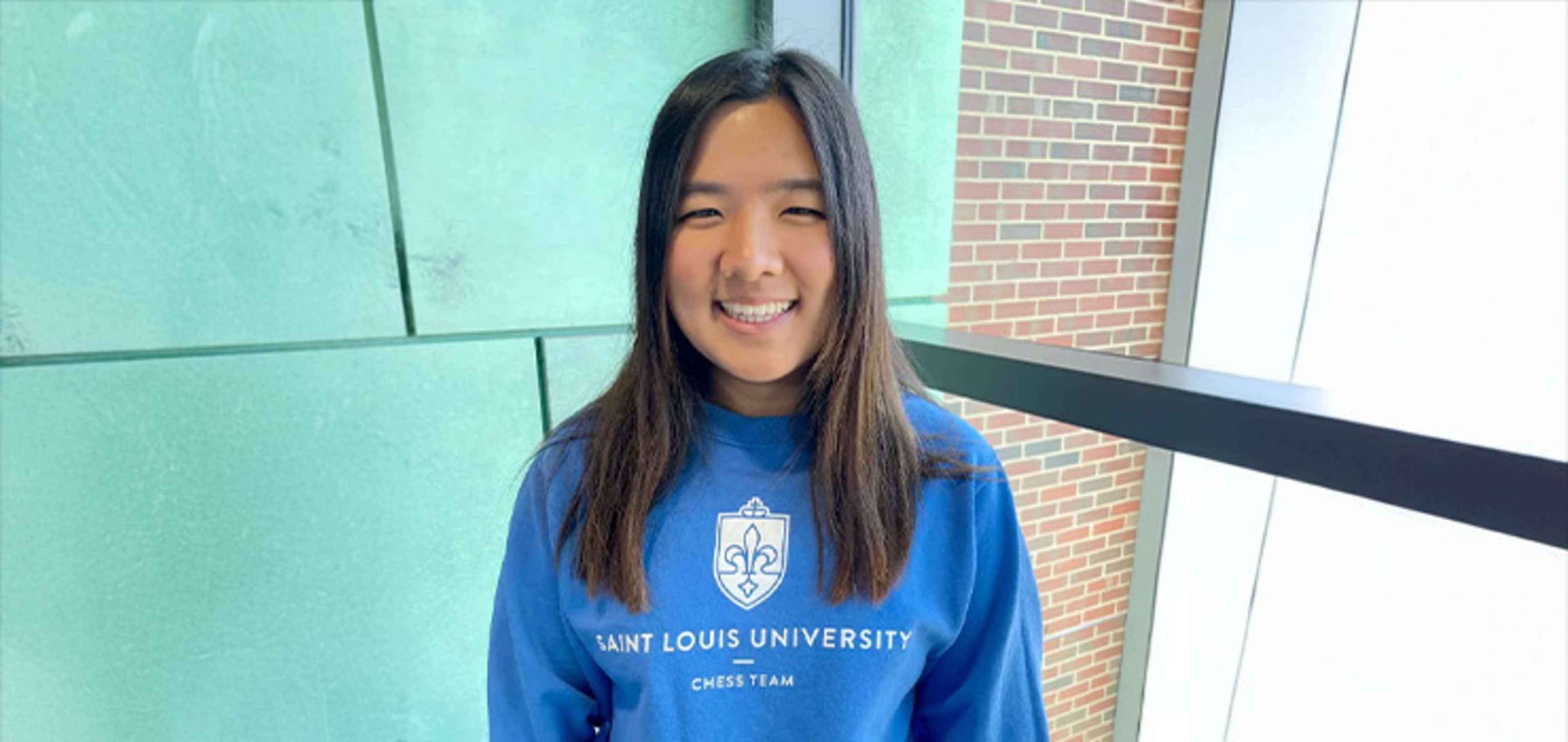 Student wearing a blue sweater next to a window