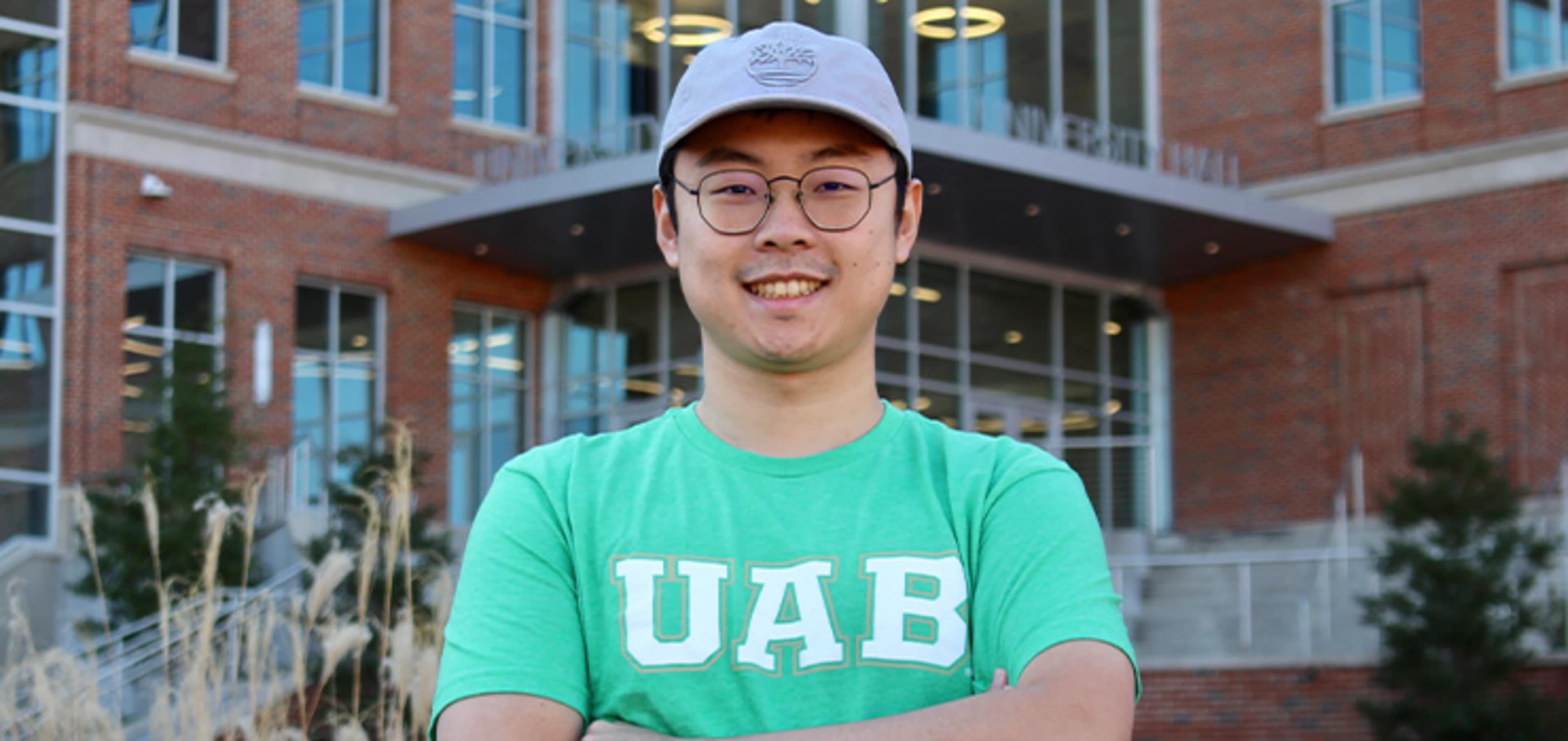 Student wearing a Green UAB t shirt in front of a building