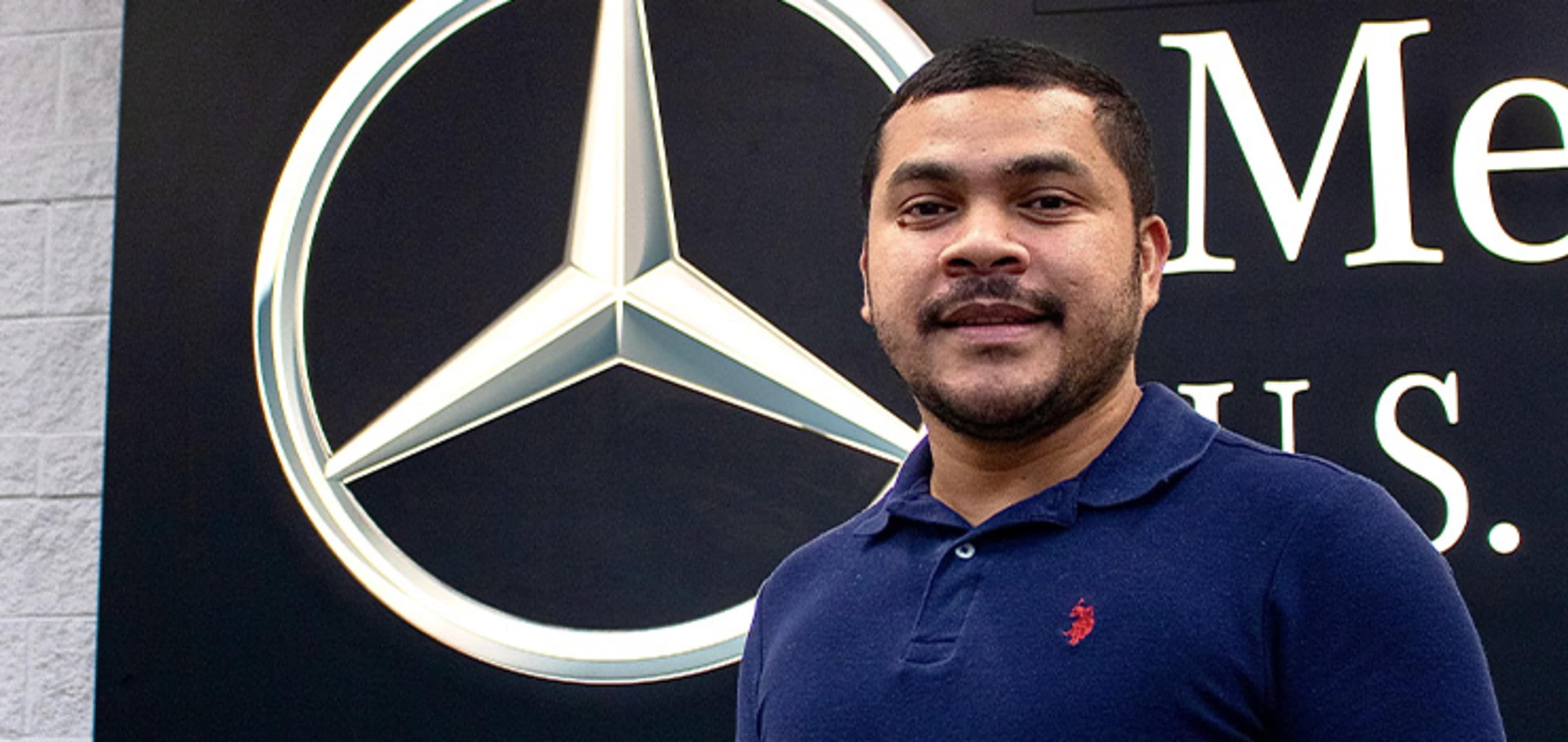 Student in front of a Mercedes Benz Logo
