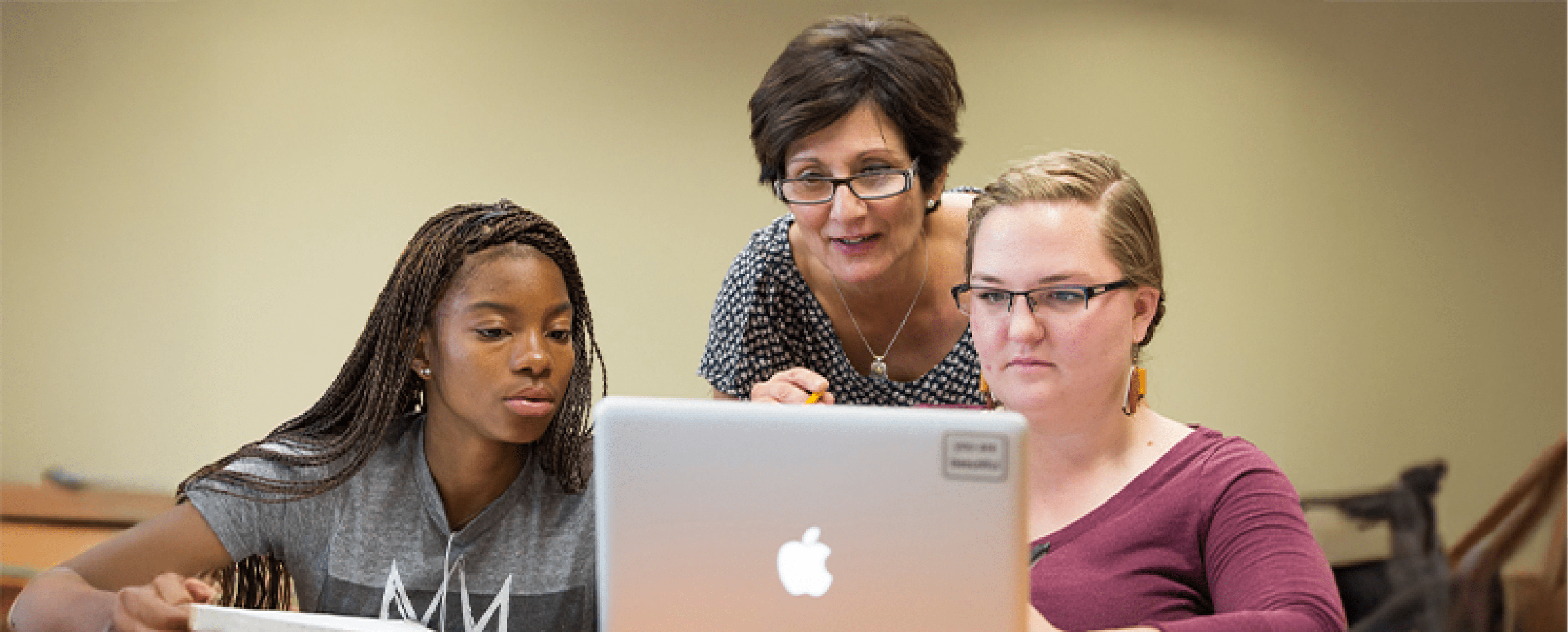 Three people looking at a macbook laptop