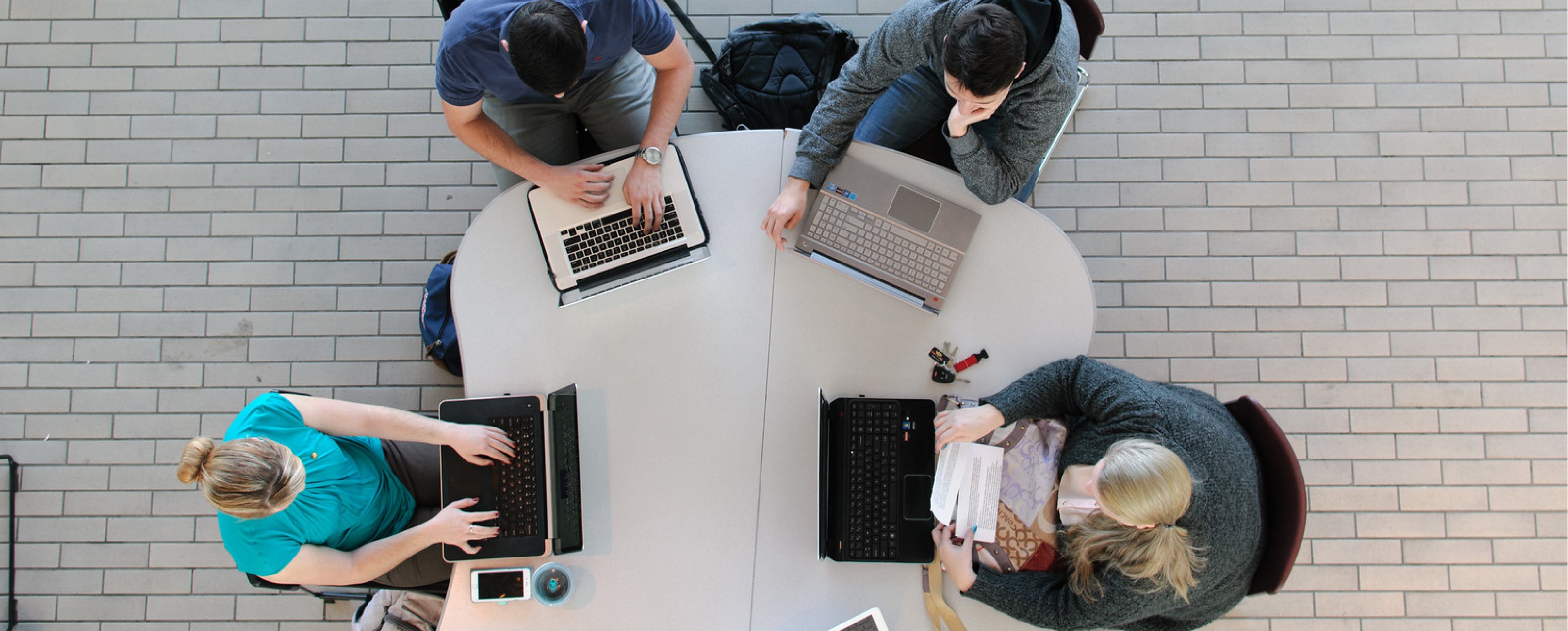 Four people siting on a table at their laptops