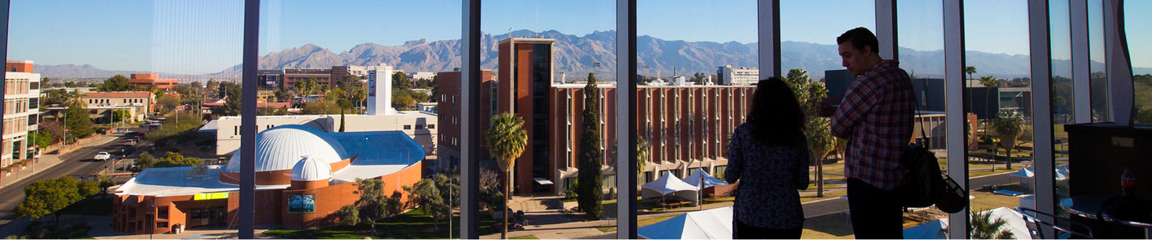 Two people standing to a window looking at the Universitiy campus
