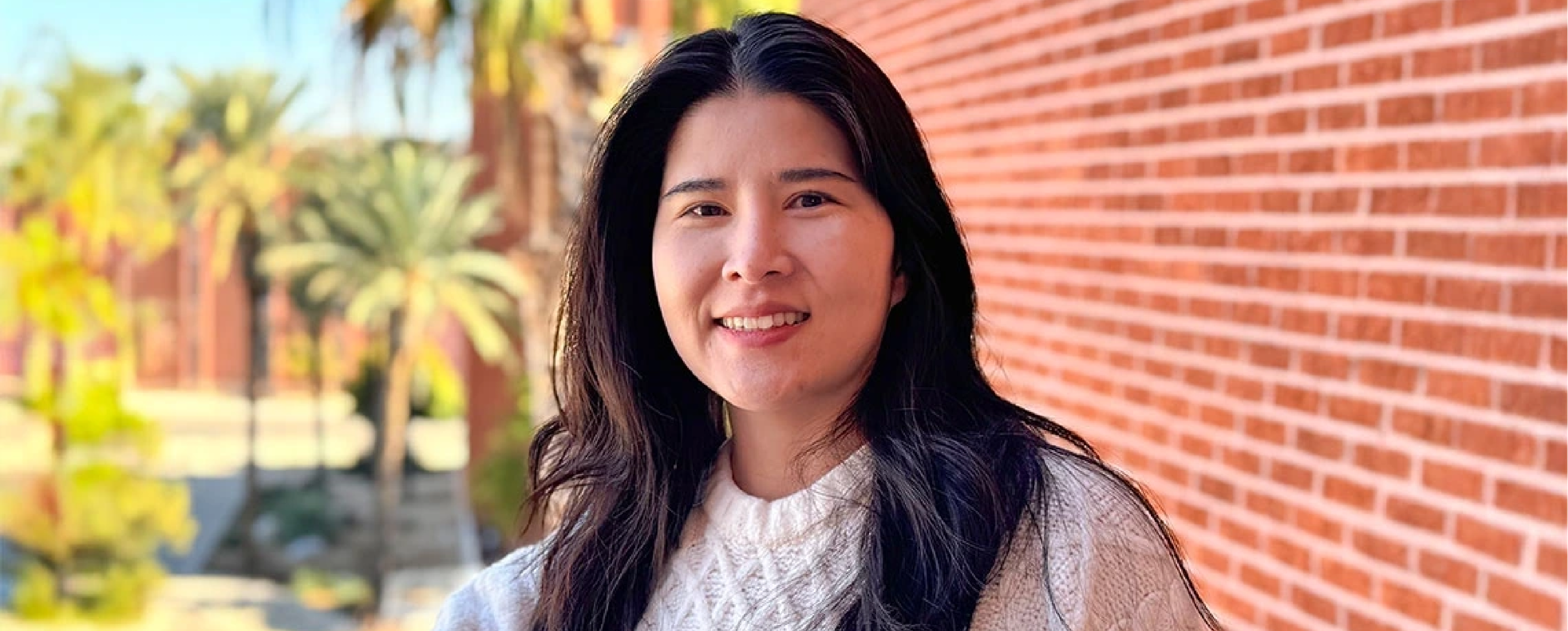 Student in font of a building looking and smiling at the camera