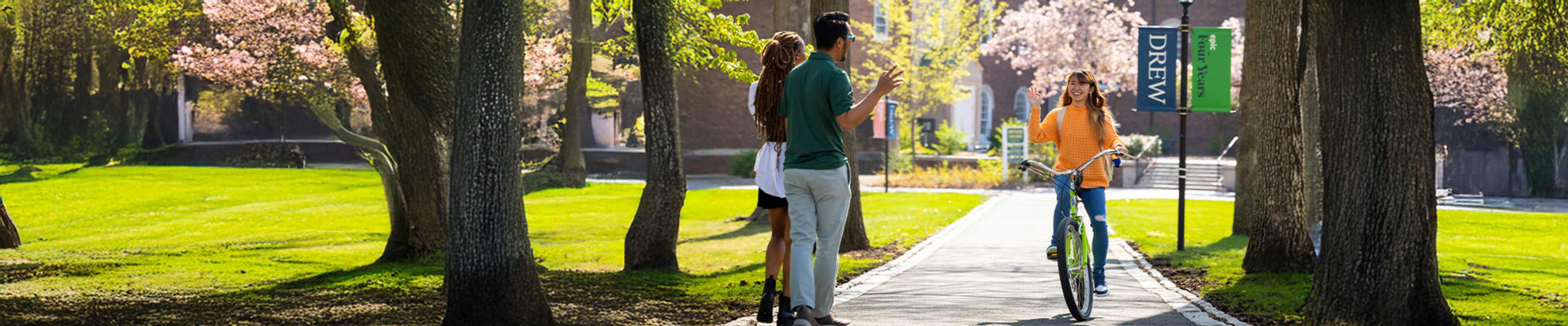 Student on a Bycicle waving at another walking students