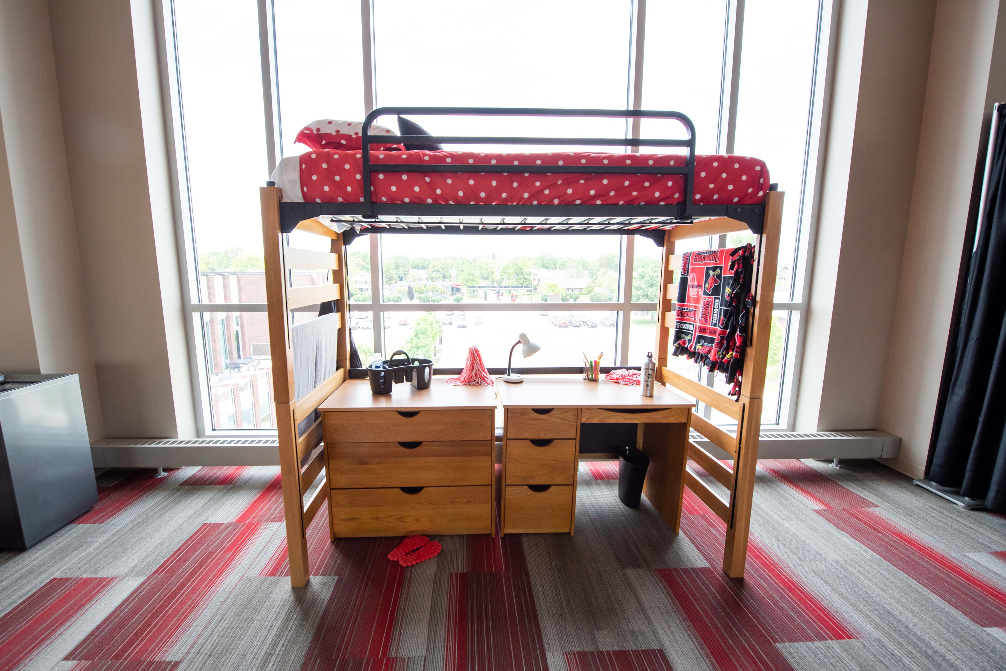 Photo of a dorm facilitie showing a desk and a bed on top of it