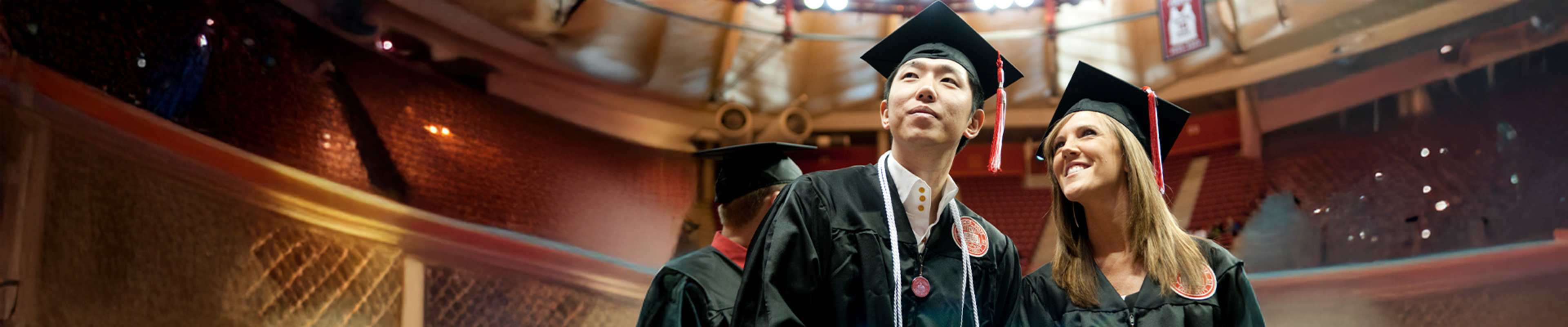 Student in front of the campus while wearing the graduation clothes