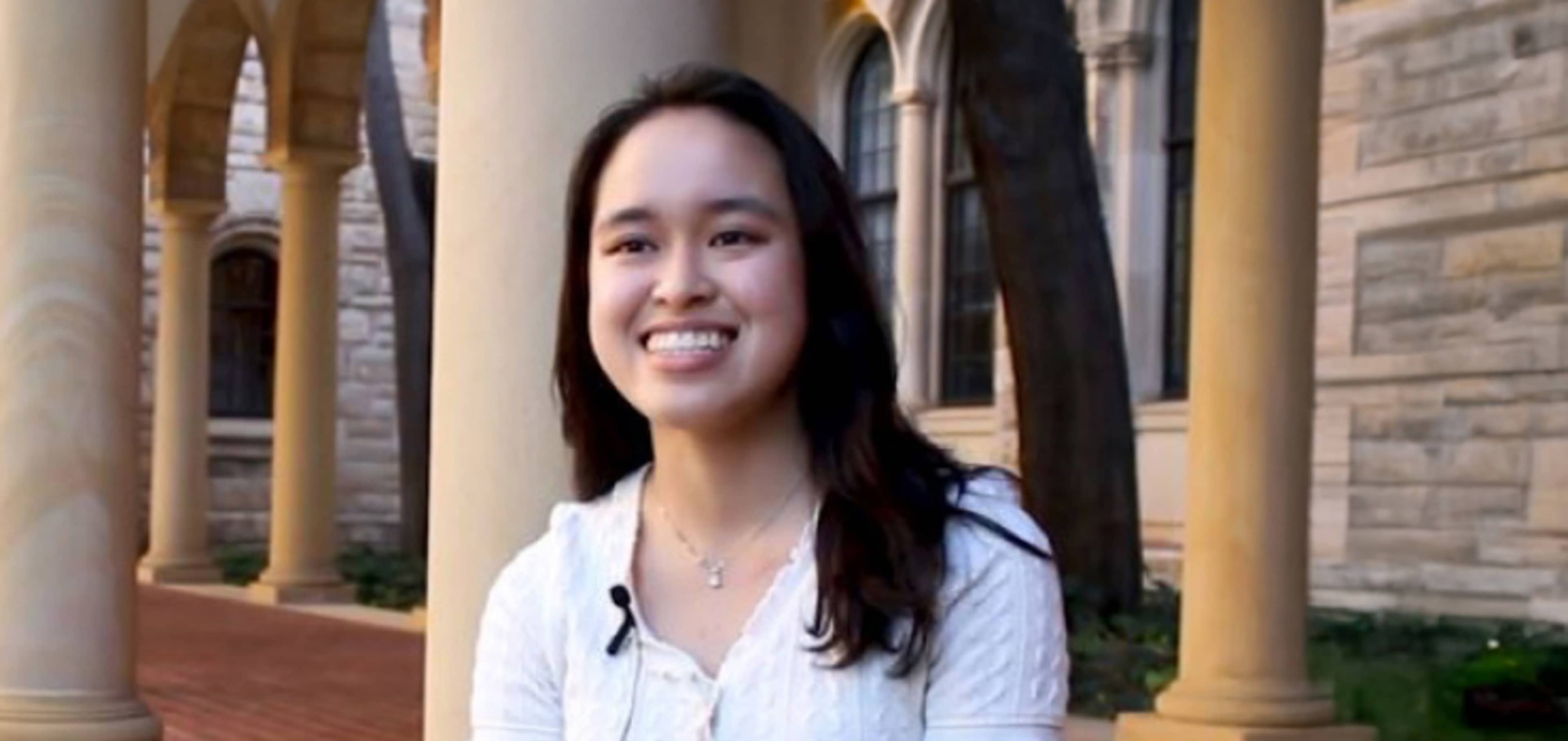 Isabelle smiling whilst sitting in front of UWA building