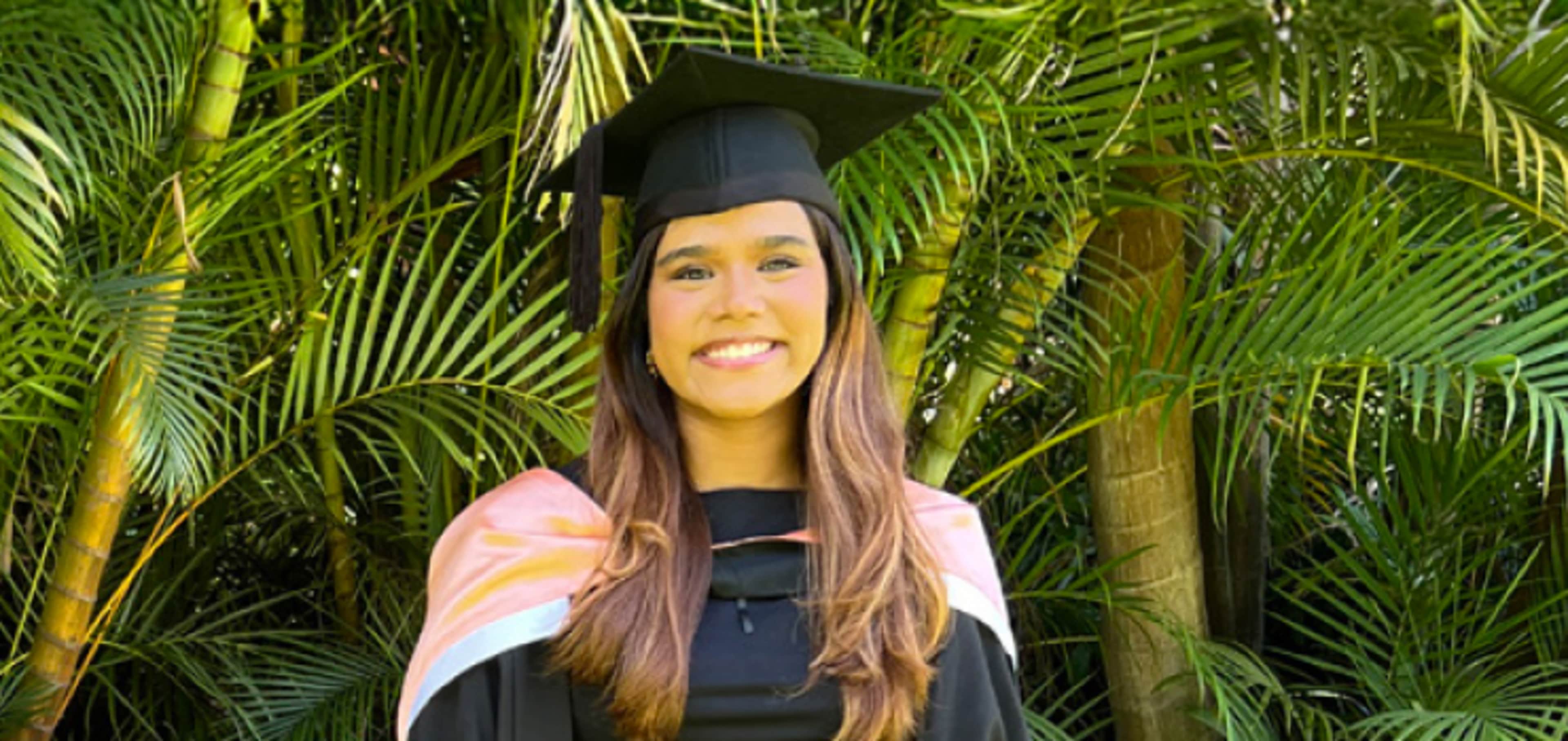 Megan in her graduation gown smiling to camera 