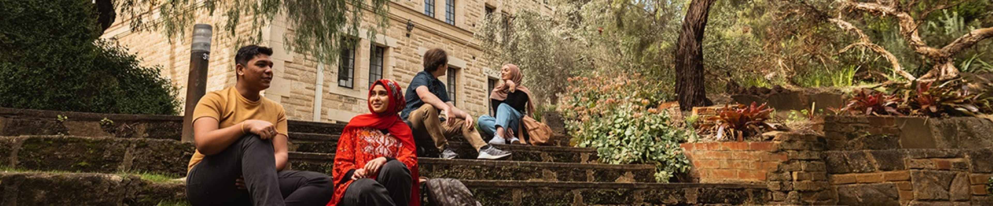 Two students sitting on steps in front of UWA College building