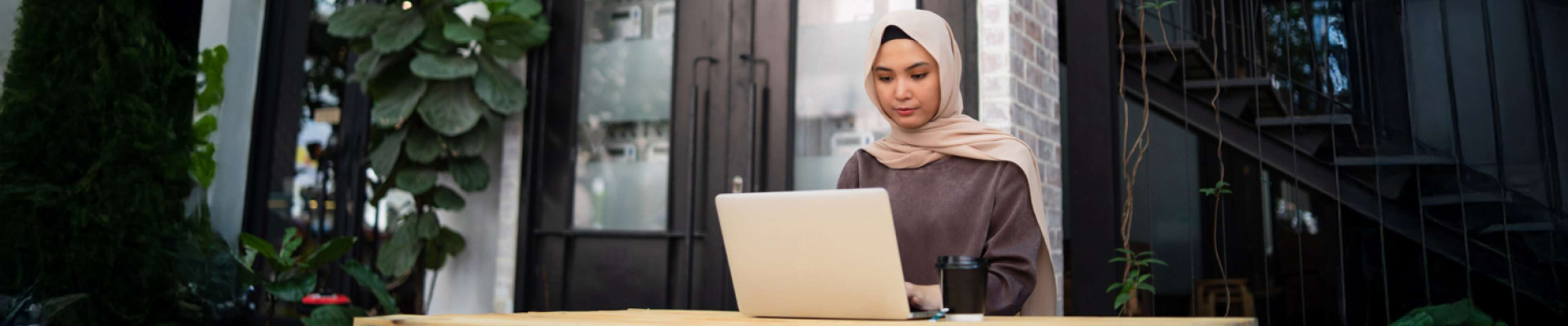 Young person sitting at table using laptop to complete application