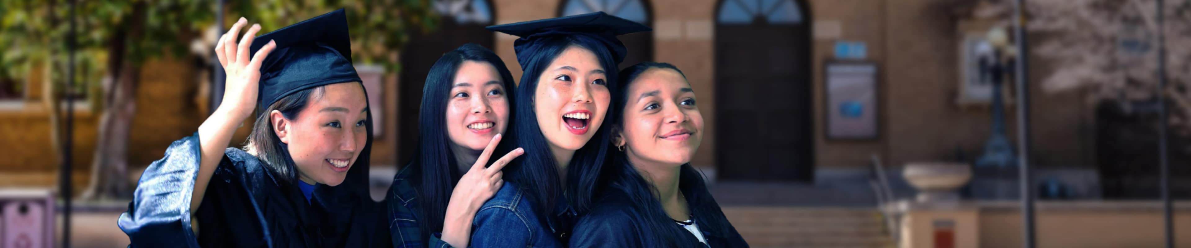Graduates posing in front of univeristy building 