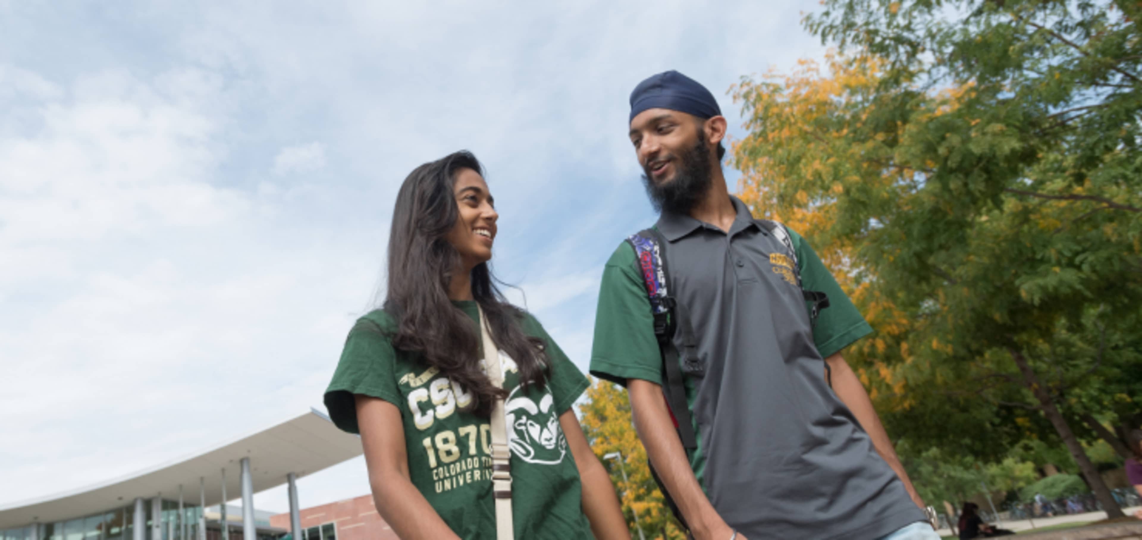 Two international students smiling and searching on a laptop