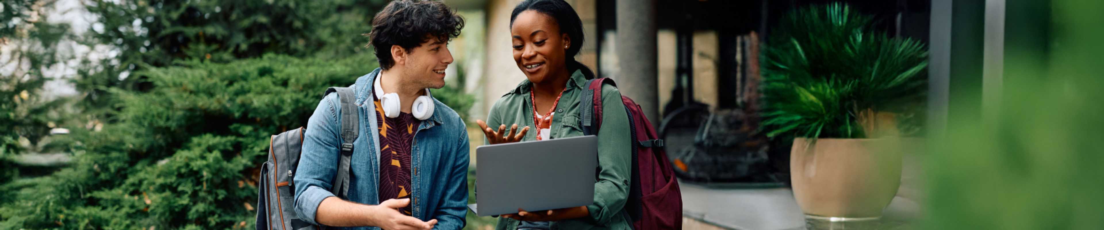 Happy student and her friend on laptop at campus