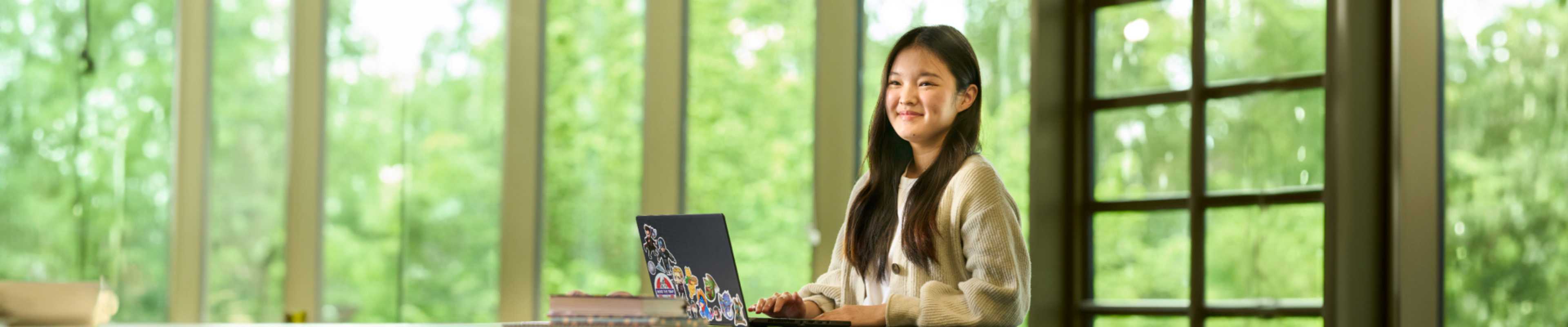 International student smiling while browsing her laptop