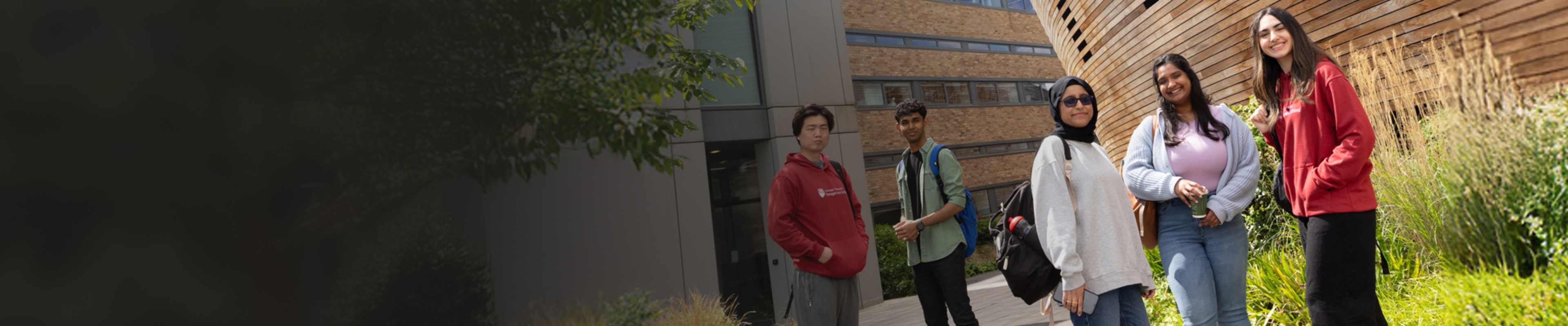 Confident group of students standing outside university building 