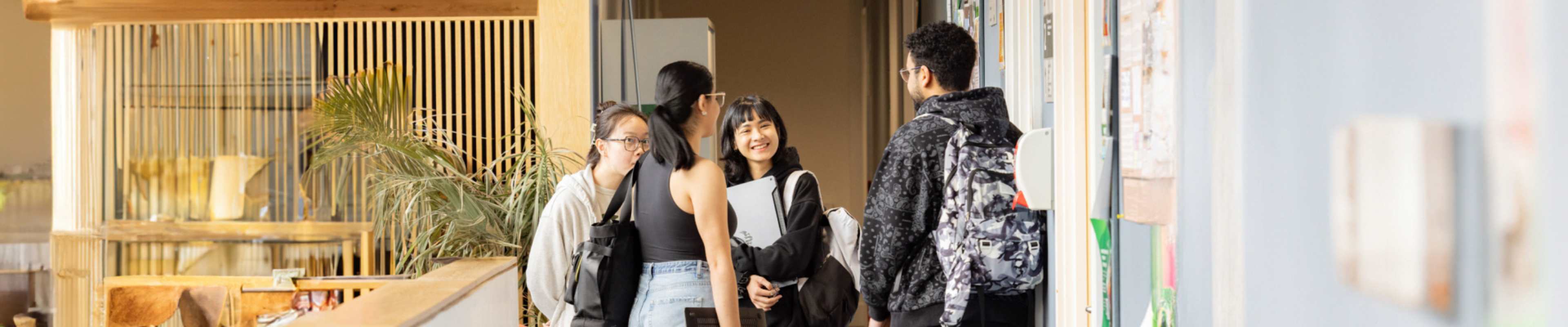 A group of international students chatting in a campus hallway