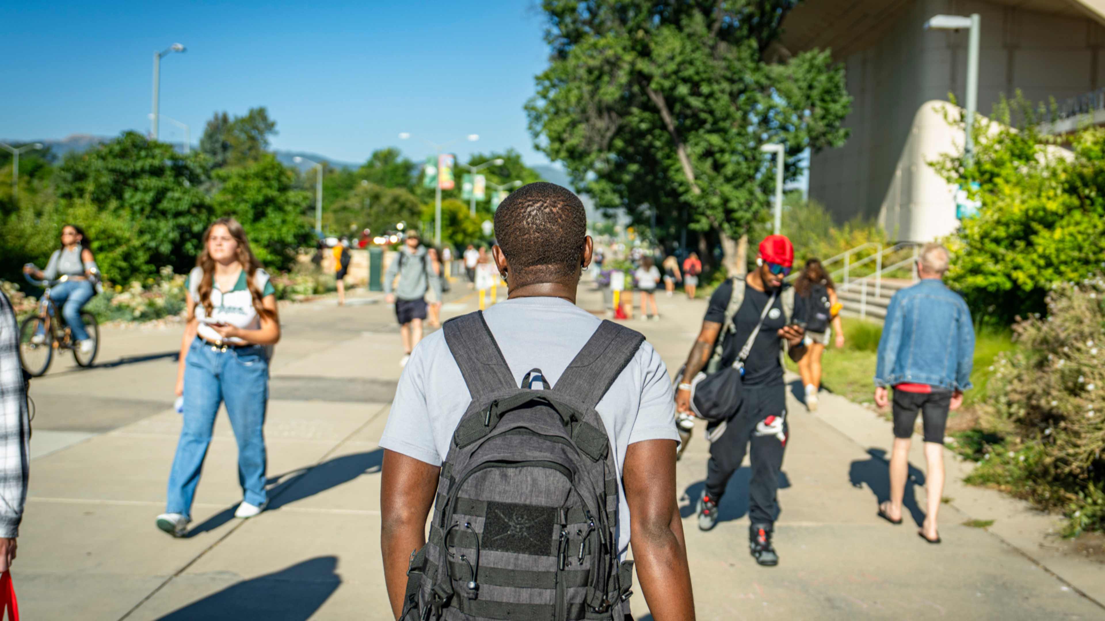 Student back to the camera walking aroun the university campus