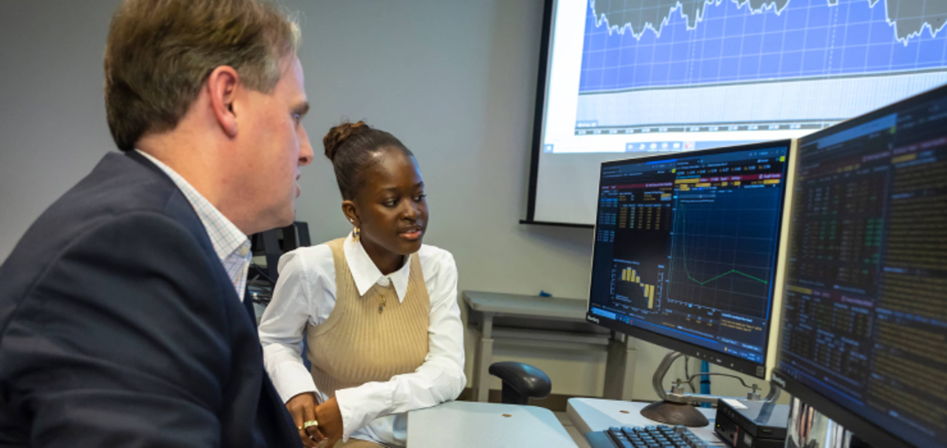 Student with finance tutor sitting at computer