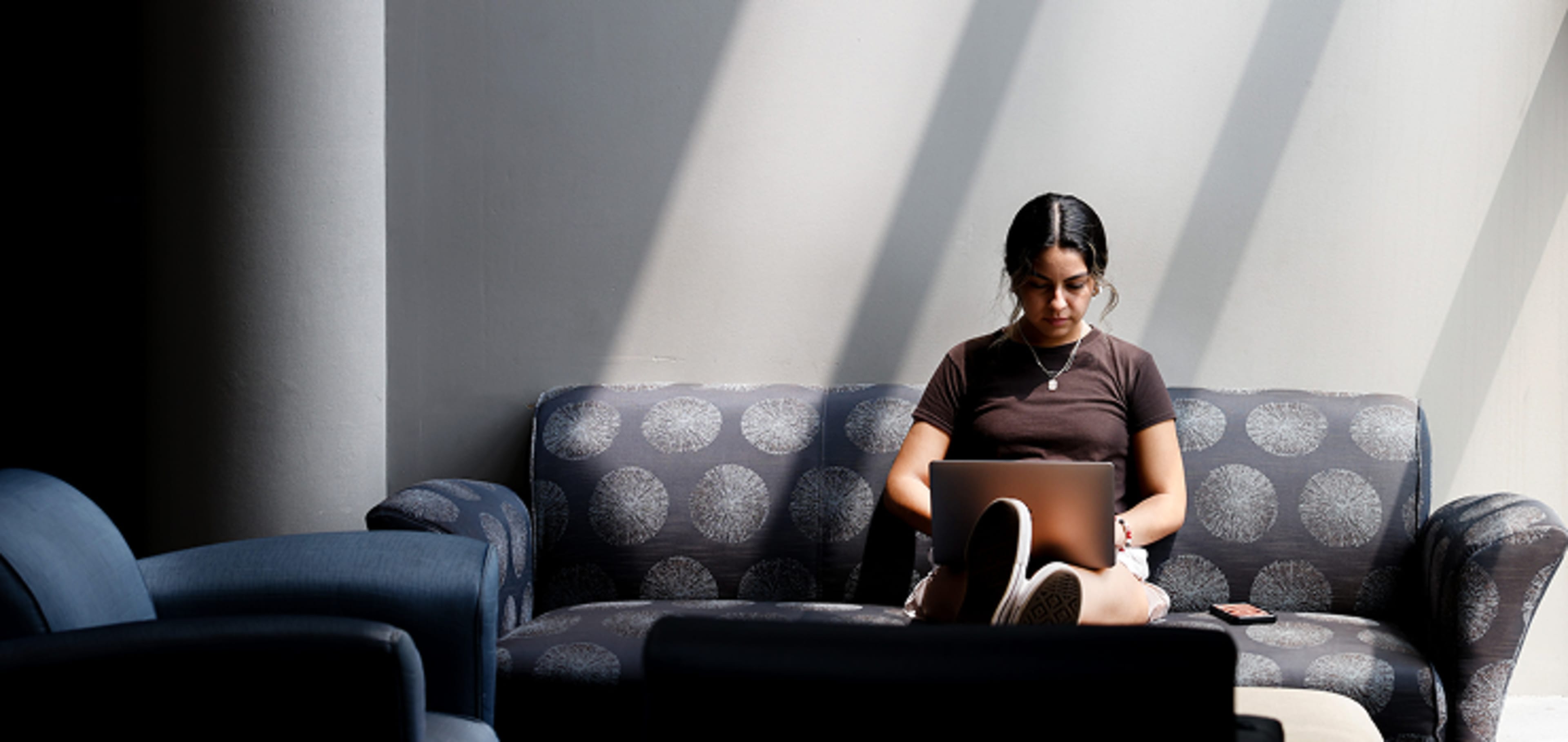 A student working on a laptop while sitting on the couch