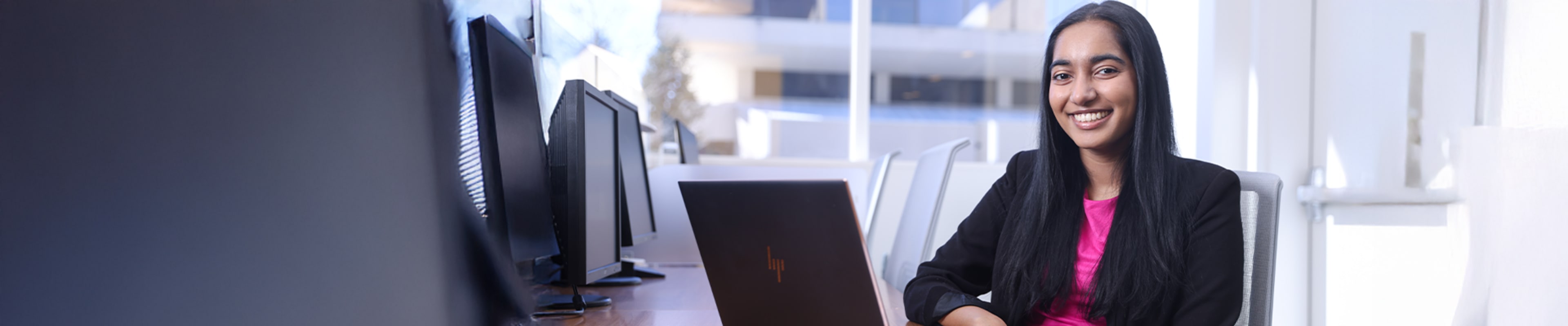 Student smiling at the camera while working in the computer